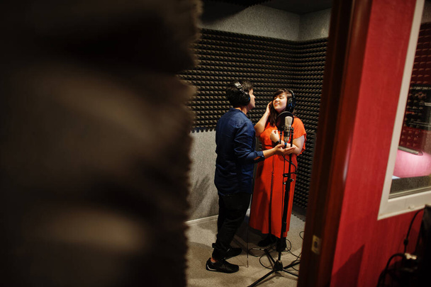 Young asian duet singers with microphone recording song in record music studio. - Foto, immagini