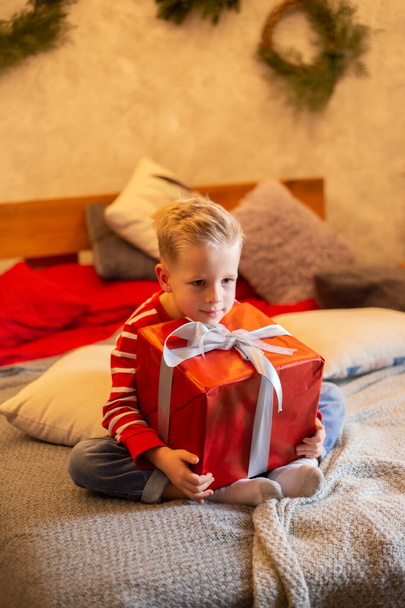 Funny child holding Christmas gift in hand. Christmas concept. - Photo, Image