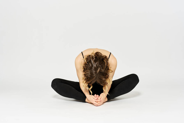 Woman in leggings meditate in a light room with her legs crossed yoga asana - Fotoğraf, Görsel