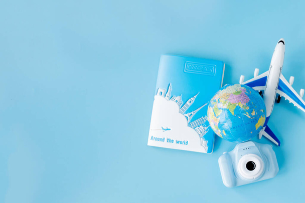 Flight tickets with passports, camera, model of airplane and globe on blue background. Summer or vacation concept. Copy space. - Photo, Image