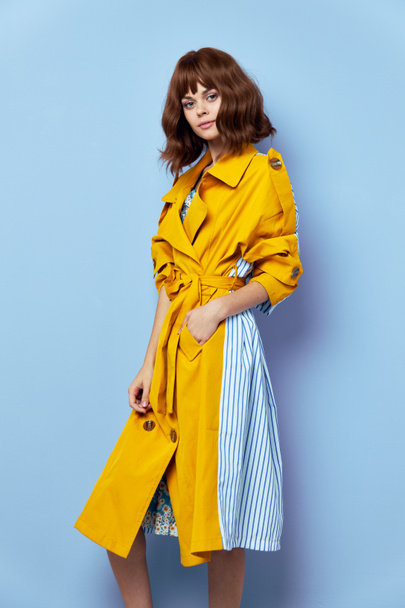 Portrait of a woman Short haired yellow coat blue background attractive  - Fotoğraf, Görsel