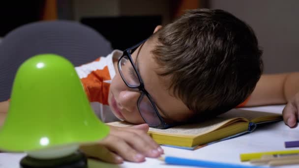 Menino curioso com óculos caiu dormindo no livro Leia na tabela. Fadiga, sono - Filmagem, Vídeo