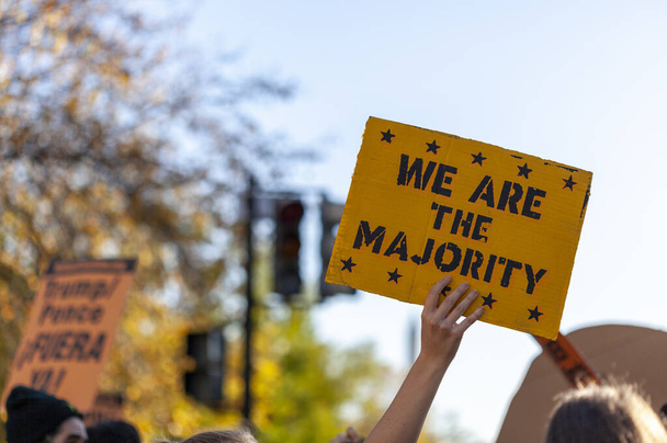 A woman is raising a banner into the air that says we are the majority. Image was taken at a demonstration near White house in Washington DC after elections.  - Photo, Image