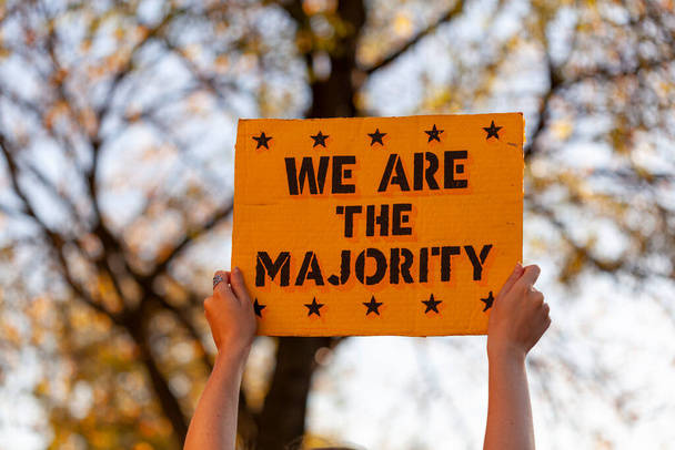 Μια γυναίκα σηκώνει ένα πανό στον αέρα που λέει ότι είμαστε η πλειοψηφία. Φωτογραφία τραβήχτηκε σε διαδήλωση κοντά στο Λευκό Οίκο στην Ουάσινγκτον μετά τις εκλογές..  - Φωτογραφία, εικόνα