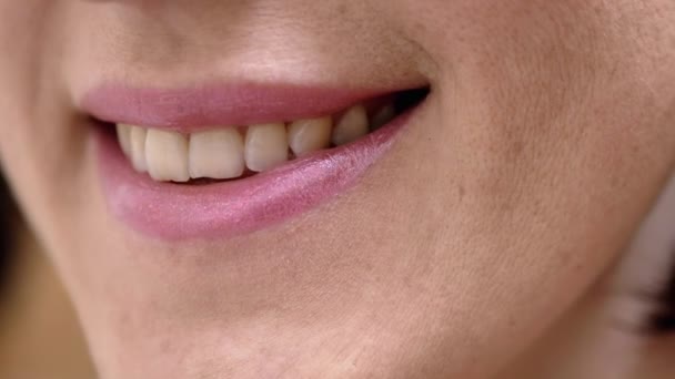 Bocca femminile sorridente con denti bianchi naturali e rossetto rosa. Concetto di salute - Filmati, video