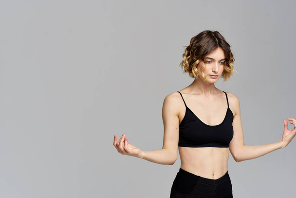 vrouw gebaren met haar handen slank figuur meditatie sport grijs achtergrond - Foto, afbeelding
