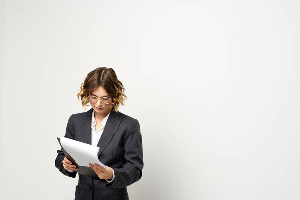 mujer de negocios en un traje con documentos en las manos fondo claro pelo rizado peinado - Foto, Imagen