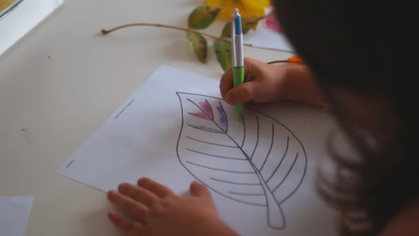 Mała dziewczynka kolorowanki duży liść obrazu na papierze z piórem - Materiał filmowy, wideo