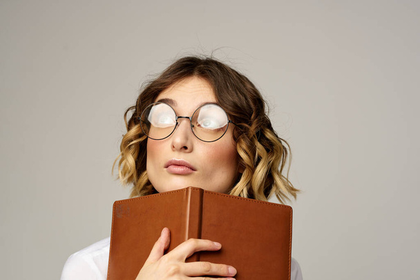 mulher com bloco de notas em mãos trabalho de negócios bege fundo óculos penteado - Foto, Imagem