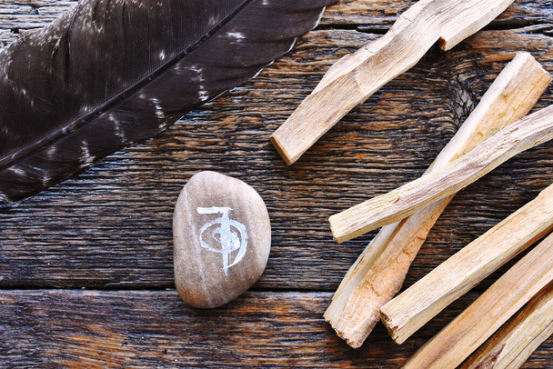 Un'immagine vista dall'alto di un simbolo di guarigione reiki e bastoncini di sbavatura palo santo su un tavolo di legno scuro.  - Foto, immagini