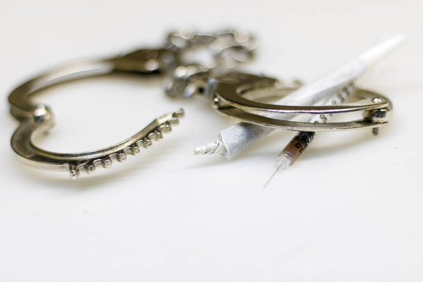 Handschellen aus silbernem Metall, platziert auf einer weißen Oberfläche und - Foto, Bild