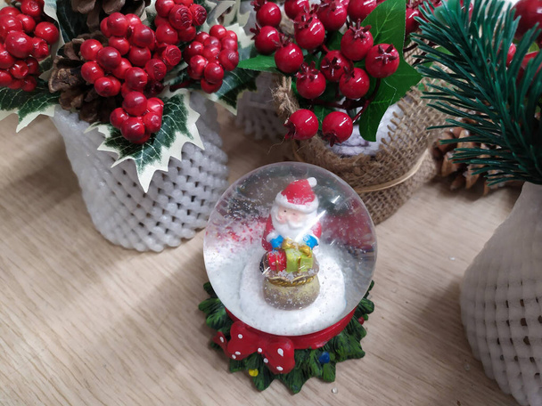 Uroczyste dekoracje w jaskrawym okresie Bożego Narodzenia 2020, piłka ze sztucznym śniegiem spadającym na Świętego Mikołaja - Zdjęcie, obraz