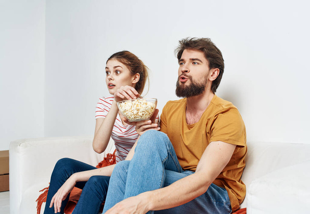 barátok férfi és nő popcorn egy tányéron beltéri kanapé belső - Fotó, kép