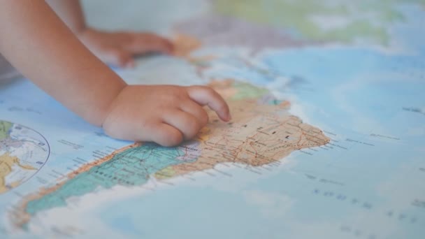 The hands of a little girl on a colorful map of South America pointing at Brazil - Materiał filmowy, wideo