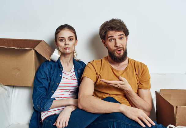 Емоційна молода пара на дивані з інтер'єром картонних коробок
 - Фото, зображення
