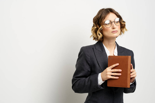 mulher de negócios em um terno com documentos em mãos luz fundo encaracolado cabelo penteado - Foto, Imagem