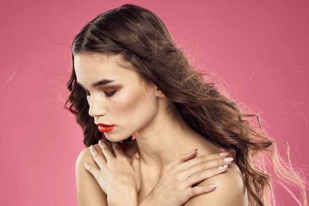Mooie vrouw met rode lippen op een roze achtergrond naakt schouders bijgesneden uitzicht - Foto, afbeelding