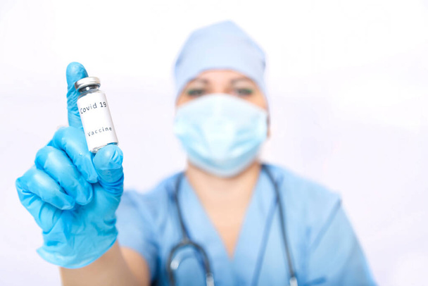 Vial with a vaccine against the virus in the hands of a doctors face in blur. - Foto, immagini