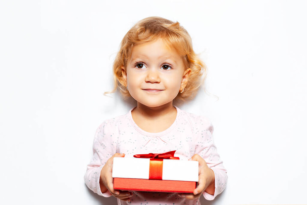 Studio portrait of child girl holding gift box with red bow no background of white color. - Photo, Image