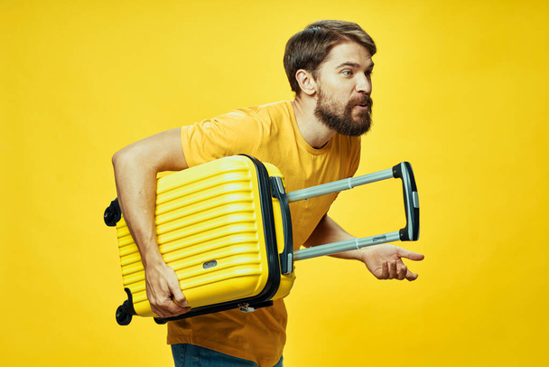 A man with a yellow suitcase sets off on a journey leaning down - 写真・画像