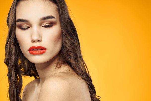 mooie brunette rode lippen kale schouders huidverzorging gele achtergrond - Foto, afbeelding
