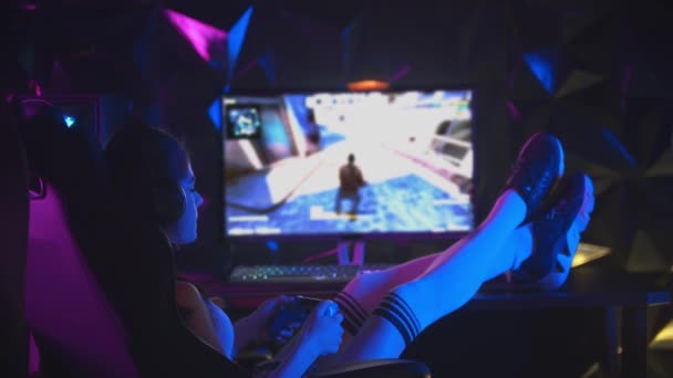 jonge aantrekkelijke vrouw het spelen van games in gaming club met joystick met haar benen op de tafel en kauwen een bubblegum - Video