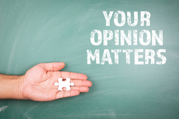 YOUR OPINION MATTERS. Piece of white puzzle in hand. Green chalk board - Photo, Image