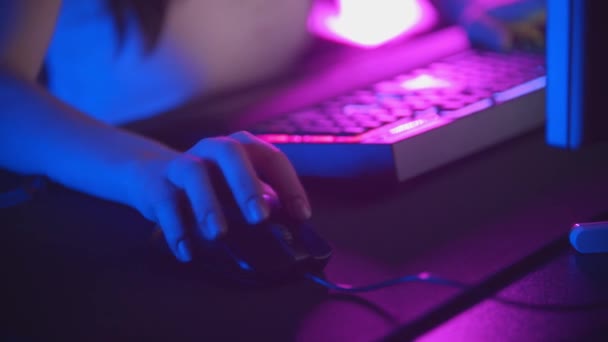 Young woman playing online games in neon gaming club - mouse and illuminated keyboard - Footage, Video