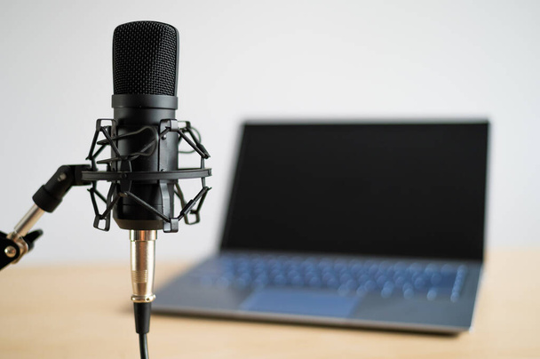 Close-up of a professional microphone on the background of a laptop. Radio broadcasters desktop - Foto, Bild