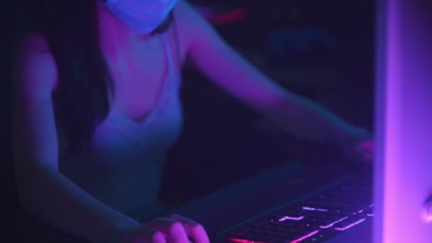 Jonge vrouw in koptelefoon en wit beschermend gezichtsmasker spelen van een online spel in gaming club - Video