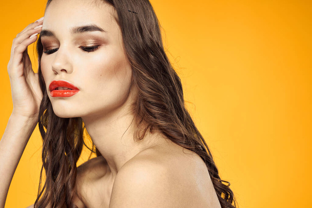beautiful brunette red lips bare shoulders skin care yellow background - Photo, Image