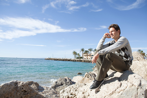 άνδρα που, καθισμένος στην ακτή - Φωτογραφία, εικόνα