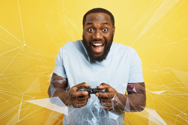 Happy man speelt met een videogame op gele achtergrond - Foto, afbeelding