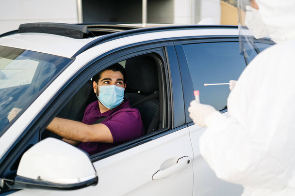 Doctor doing a PCR test COVID-19 on a patient through the car window.  - Fotografie, Obrázek