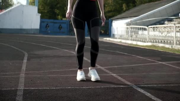 sottile corridore caucasico in abbigliamento sportivo inizia a correre dal blocco sulla pista dello stadio - Filmati, video