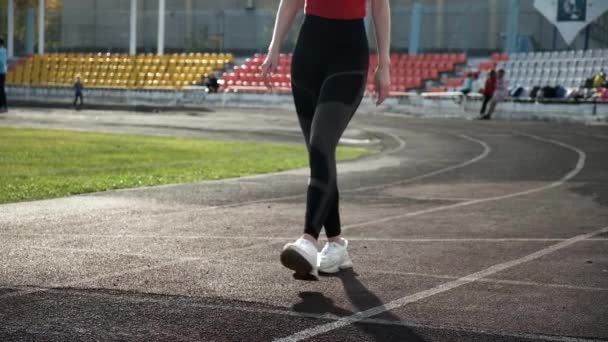 sottile corridore caucasico in abbigliamento sportivo inizia a correre dal blocco sulla pista dello stadio - Filmati, video