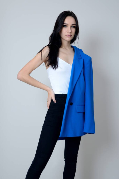 Confident, young woman stands with blue jacket. Beautiful brunette, Miss Lower Silesia poses at home, indoor photo session.  - 写真・画像