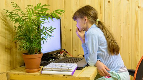 A schoolgirl thoughtfully reads a problem in an online lesson with distance learning - Photo, Image
