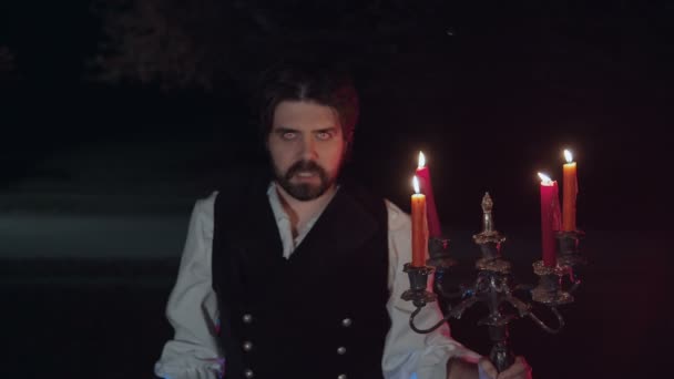 Vampire with candles outside and glowing eyes - Footage, Video
