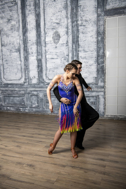 Dans kostümlü güzel bir çift koridorda Latin dansı yapıyor. - Fotoğraf, Görsel