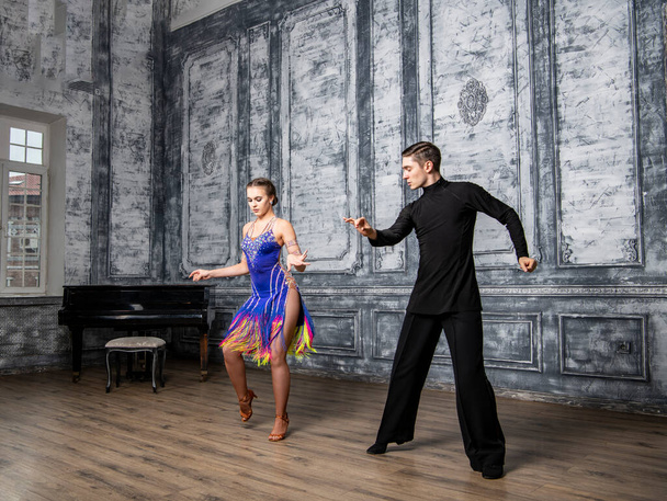 schönes Paar mit Tanzkostümen, die lateinische Tänze im Saal tanzen - Foto, Bild
