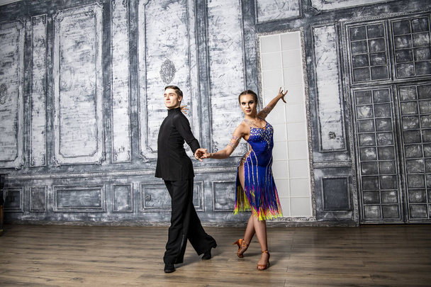 beautiful couple with dance costumes dancing latin dances in the hall - Фото, зображення