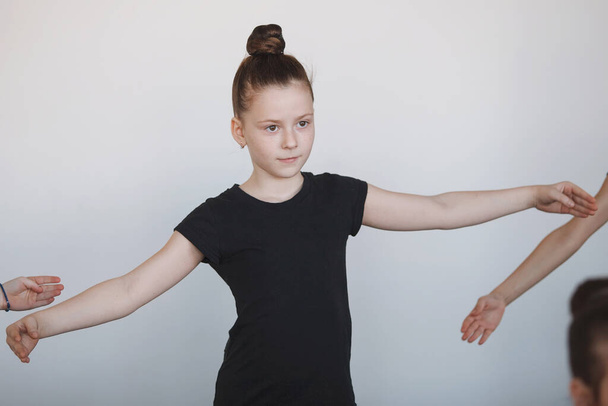 ダンス、バレエ、リズム体操にポーズをとる少女10代の肖像。黒のレオタード、ブンの髪、振付、注意。選択的焦点. - 写真・画像