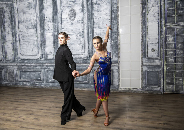 красивая пара в танцевальных костюмах танцует латинские танцы в холле - Фото, изображение