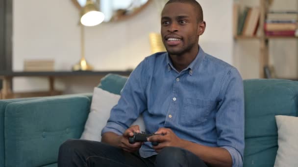 Young African Man Celebrating Success on Video Game on Sofa - Footage, Video