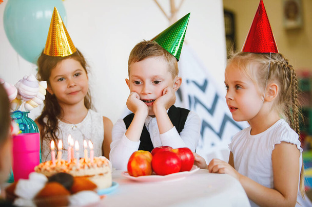 I bambini in berretti e vestiti eleganti si divertono e godono il loro compleanno con palloncini. - Foto, immagini