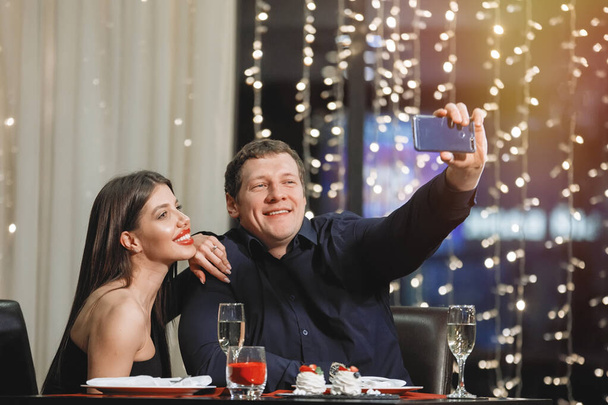 Homme et femme prennent selfie sur smartphone à la table du café. - Photo, image