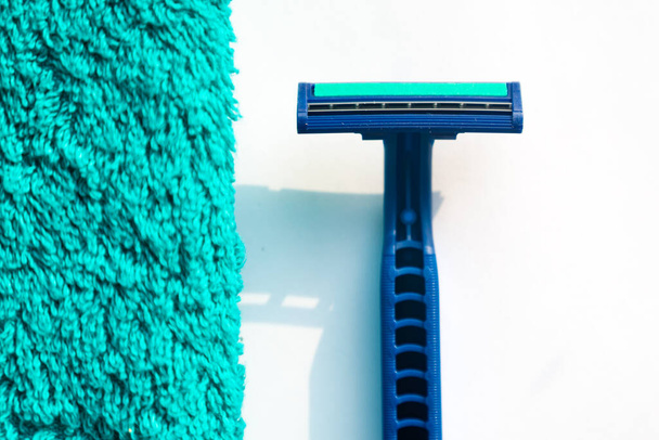 The razor lies near green towel. White background - Фото, изображение