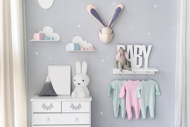 Φωτεινό παιδικό δωμάτιο για νεογέννητο μωρό με commode, λαγουδάκι παιχνίδια, διακόσμηση σπιτιού και ρούχα φορούν στο ράφι κάτω από το ράφι στο Nordic διαμέρισμα εσωτερικό στυλ - Φωτογραφία, εικόνα
