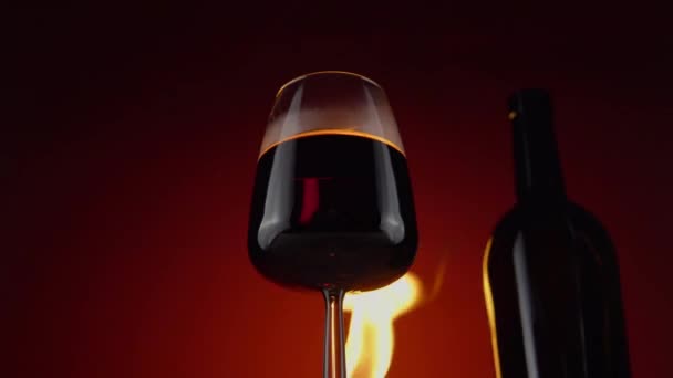 Weinglas und Flasche, Feuer im Hintergrund. Alkoholgetränke aus nächster Nähe - Filmmaterial, Video
